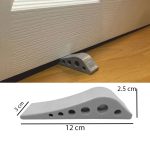 Grey rubber door stopper wedge with honeycomb non-slip design placed under door on wooden floor for secure door holding