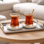 Turkish tea set with 6 slim glass cups gold rim saucers and gold spoons on tray in modern living room