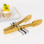 Gold stainless steel serving tong with scalloped edges used for cooking and serving food in kitchen