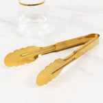 Gold stainless steel serving tong with scalloped edges used for cooking and serving food in kitchen