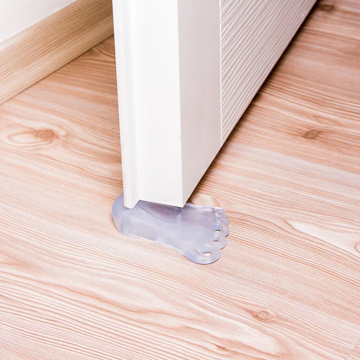 Foot shaped anti slip door stopper made of TPR placed under door on white background