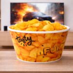 Popcorn snack bowl with chips on table in front of TV in modern living room setting