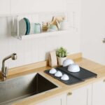 Expandable tabletop dish dryer rack with drainage spout and tiered surface in white and grey for kitchen use