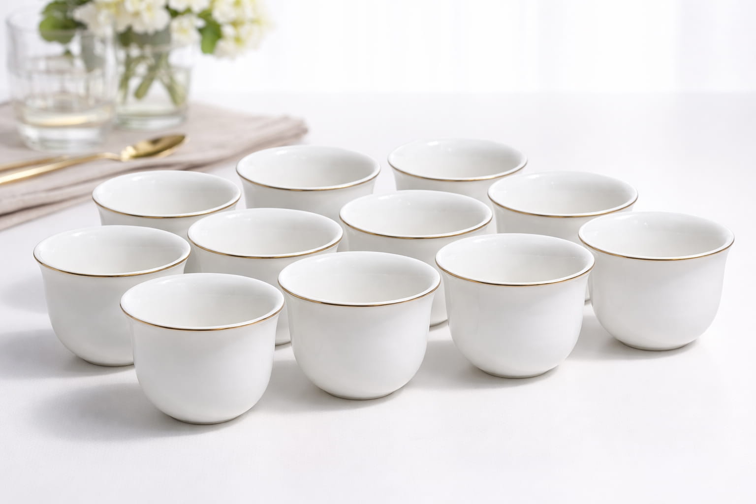 Set of 12 white ceramic coffee cups with elegant gold rim on white background