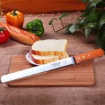 Long serrated bread knife with wooden handle slicing bread cleanly