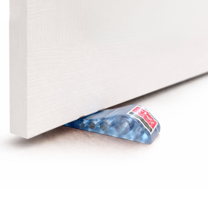 Transparent rubber door stopper wedge holding door open on wooden floor in modern room