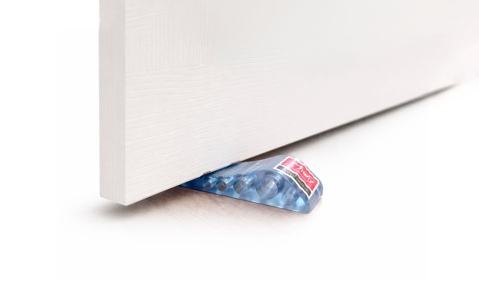 Transparent rubber door stopper wedge holding door open on wooden floor in modern room