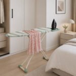 metallic ironing board with patterned cover and foldable metal legs on white background