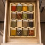 Bamboo spice rack with 16 airtight glass jars and bamboo spoons on white background
