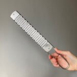 long parmesan cheese grater with ergonomic handle on white background for cheese citrus chocolate and vegetables.