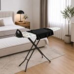 metallic ironing board with patterned cover and foldable metal legs on white background