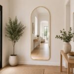 Gold arched full-length floor mirror with slim metal frame, freestanding stand and wall-mount hooks, size 59x165 cm.