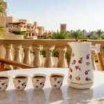 Rose-pattern 1L insulated thermos with wood handle and 12 ceramic Arabic coffee cups on a hospitality serving set.