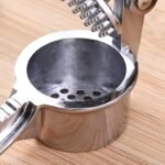 Curved stainless steel garlic and ginger crusher press dishwasher safe kitchen tool 15 cm long.