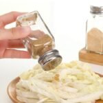 glass salt shaker with a stainless steel screw-on lid and spice dispensing holes