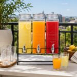 glass beverage dispensers with leak-proof taps on a black iron stand for serving water, juice, lemonade, and iced tea.